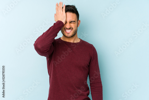 Photography Young caucasian man isolated on blue background forgetting something, slapping forehead with palm and closing eyes
