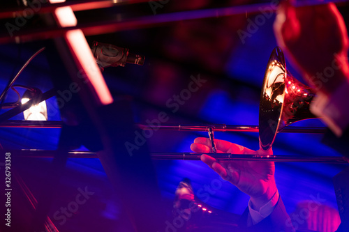 Musicians of a big band trombone section are laying down some smooth jazz during a live show in a venue with red lights and blue lights making streaks in fron of the camera photo