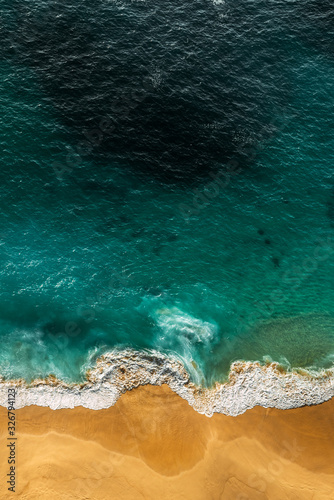 Beautiful sandy beach with turquoise sea, vertical view. Drone view of tropical turquoise ocean beach Nusa penida Bali Indonesia. Lonely sandy beach with beautiful waves. Beaches of Indonesia.