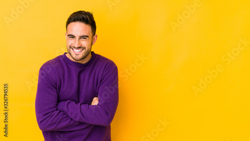 Young caucasian man isolated on yellow bakground laughing and having fun.