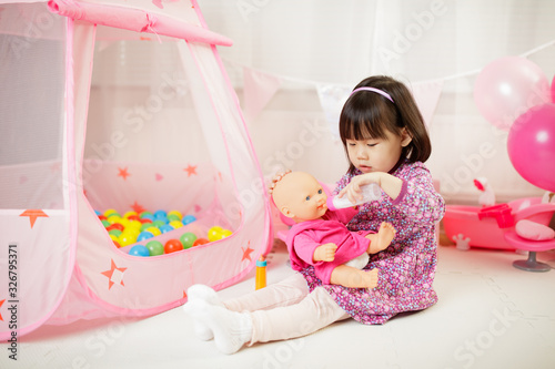 Tableau sur toile toddler girl pretend play baby care at home against white background