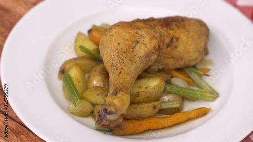 Chicken leg with vegetables served in white plate, on wooden and checkered tablecloth background. Close-up  Stock Video