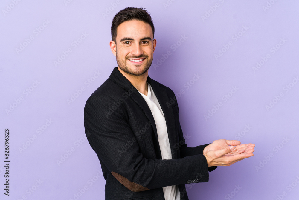Young caucasian man isolated on purple background holding a copy space on a palm. Young caucasian man isolated on purple background holding a copy space on a palm.