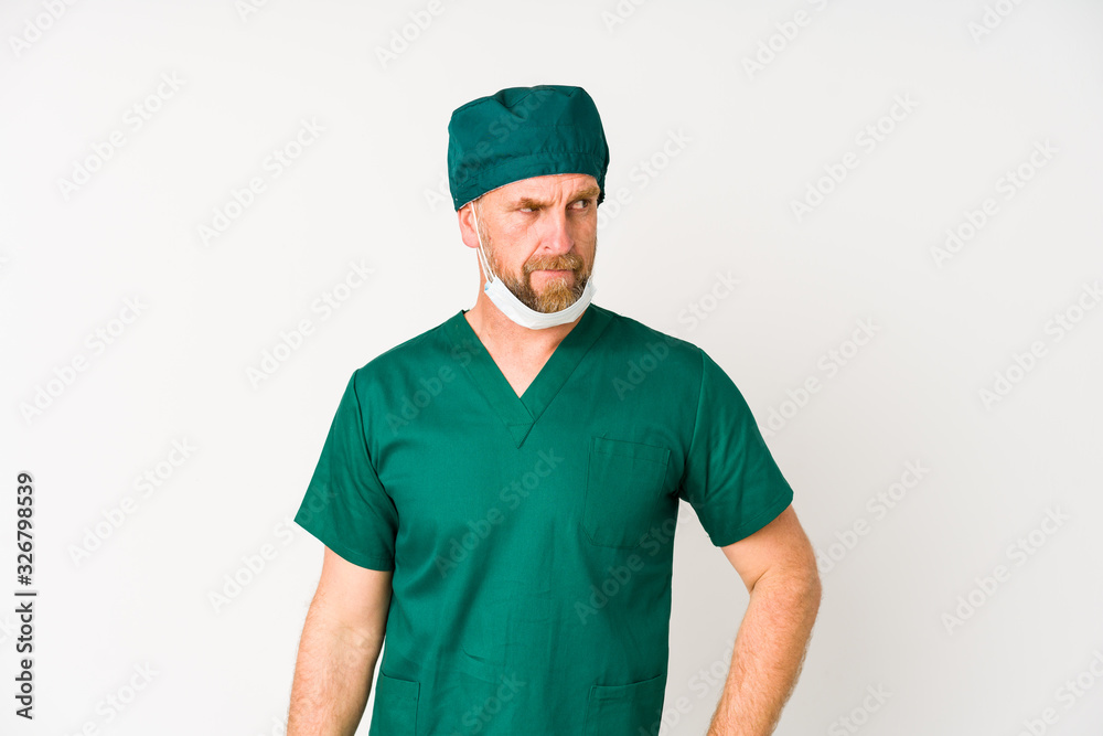 Surgeon senior man isolated on white background confused, feels doubtful and unsure. Surgeon senior man isolated on white background confused, feels doubtful and unsure.