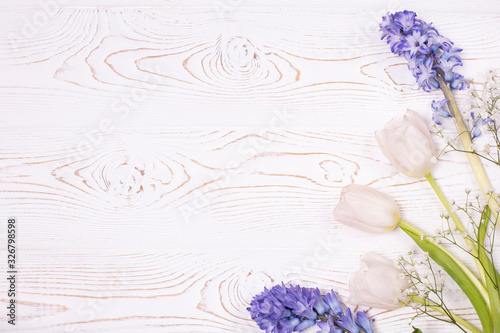 Top view on blue hyacinth flowers and white tulips on a white wooden table with space for text