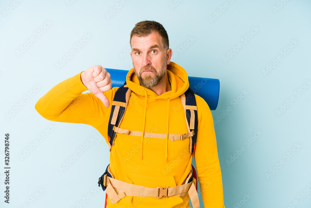 Senior hiker man isolated on blue background showing a dislike gesture, thumbs down. Disagreement concept.