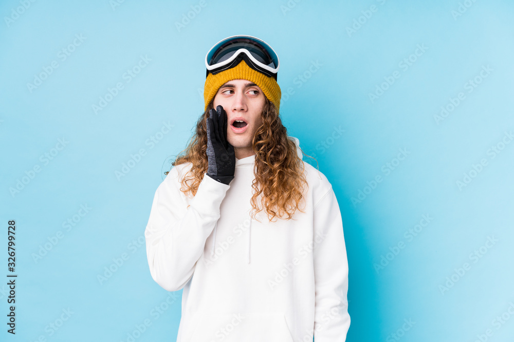Young caucasian man wearing a ski clothes isolated is saying a secret hot braking news and looking aside Young caucasian man wearing a ski clothes isolated is saying a secret hot braking news and looking aside