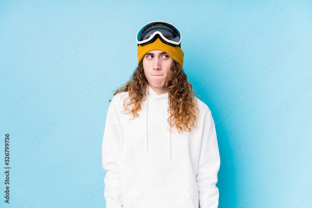 Young caucasian man wearing a ski clothes isolated  confused, feels doubtful and unsure.