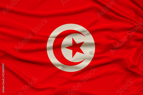 beautiful photo of the national flag of Tunisia on delicate shiny silk with soft draperies, the concept of state power, country life, horizontal, close-up, copy space