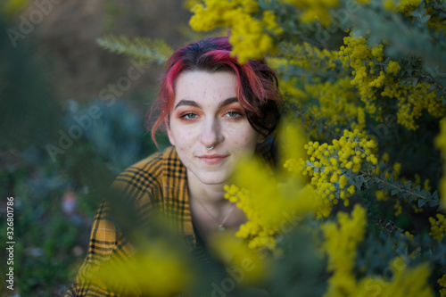 emo woman with red hair and septum piercing smiling at the camera