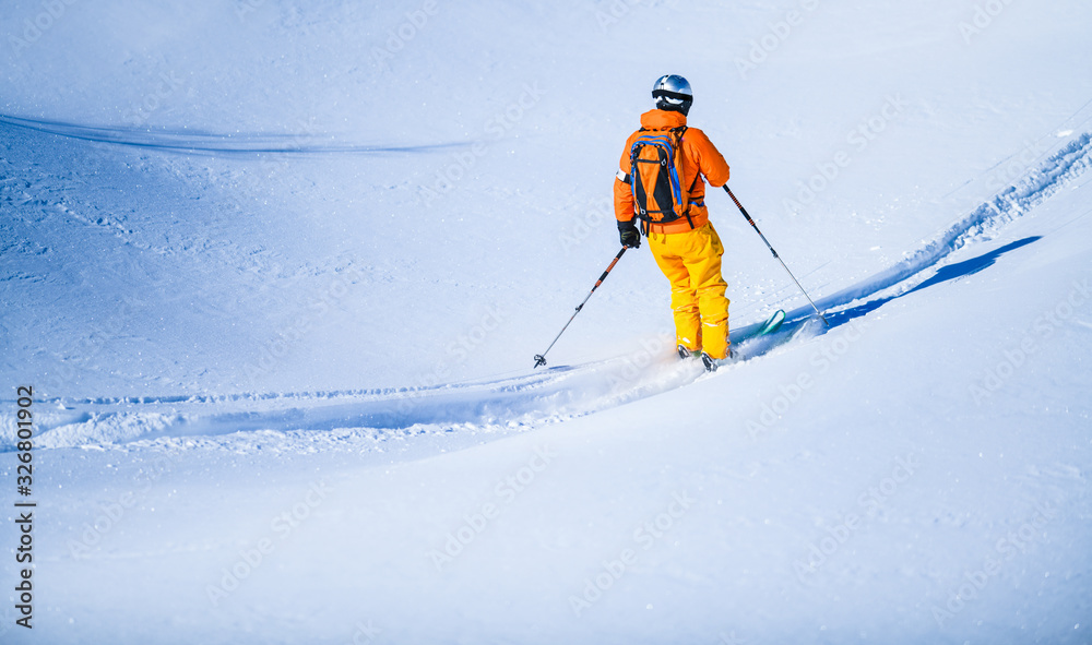 Free ride skier on heavy deep fresh snow, skiing down steep slope in winter  mountains.