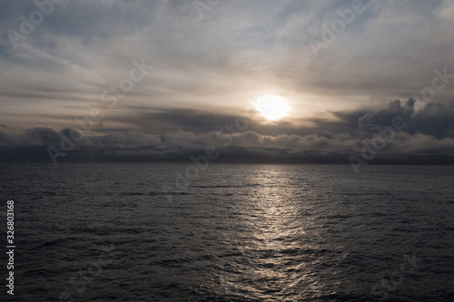 Sonnenuntergang mit dramatischem Wolkenhimmel im Fjord von der Seeseite aus
