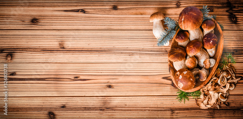 Fresh boletus mushrooms in basket and dry mushroom on wooden rustic table, overhead shot.