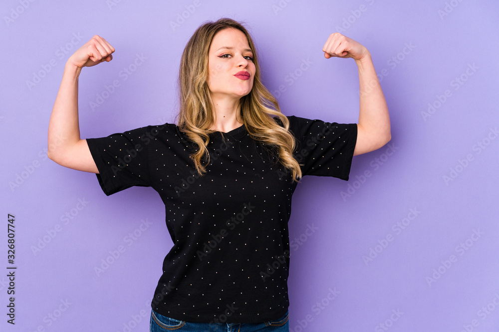 Young caucasian woman isolated on purple background showing strength gesture with arms, symbol of feminine power Young caucasian woman isolated on purple background showing strength gesture with arms, symbol of feminine power