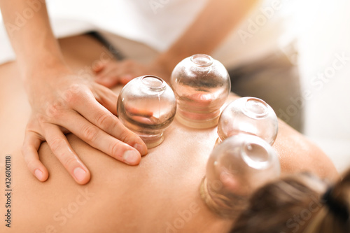 Fotografija Detail of a woman therapist hands giving cupping treatment on back