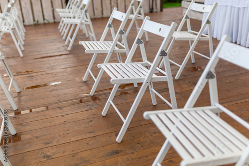 Rows of white chairs in rows on the beach sand. Conference or outdoor wedding. Watching a movie or a street theater.