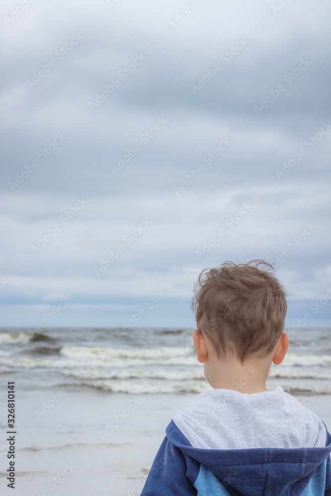 The little boy looks at the rough sea waves