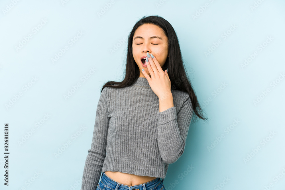 Φωτογραφία Young chinese woman isolated on a blue background yawning showing a tired gesture covering mouth with hand