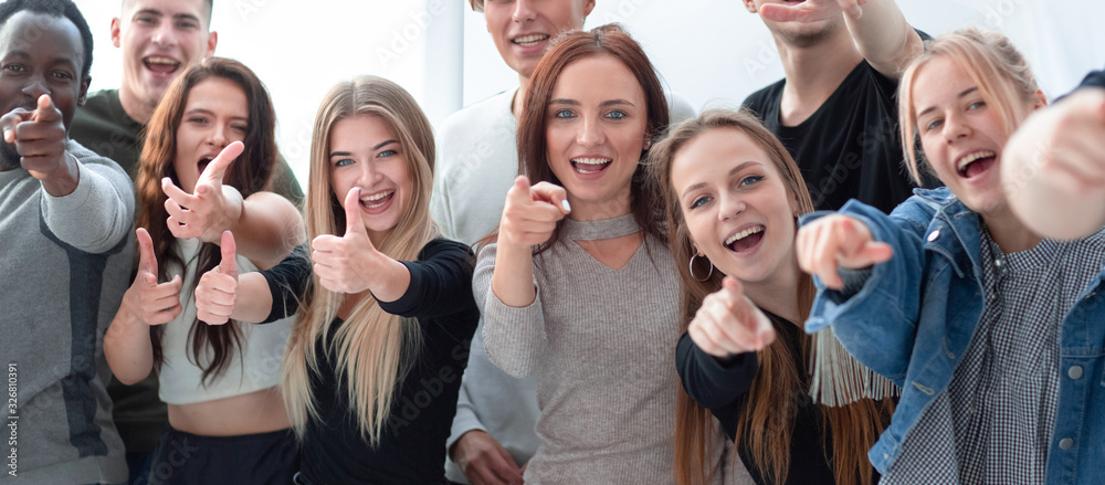 group of smiling young people pointing at one point