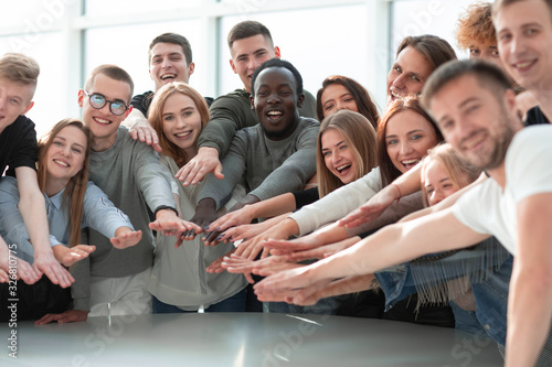 group of smiling young people joining their hands