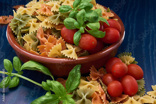 loop pasta, bright natural colors, basil green and red tomatoes, with blue scene