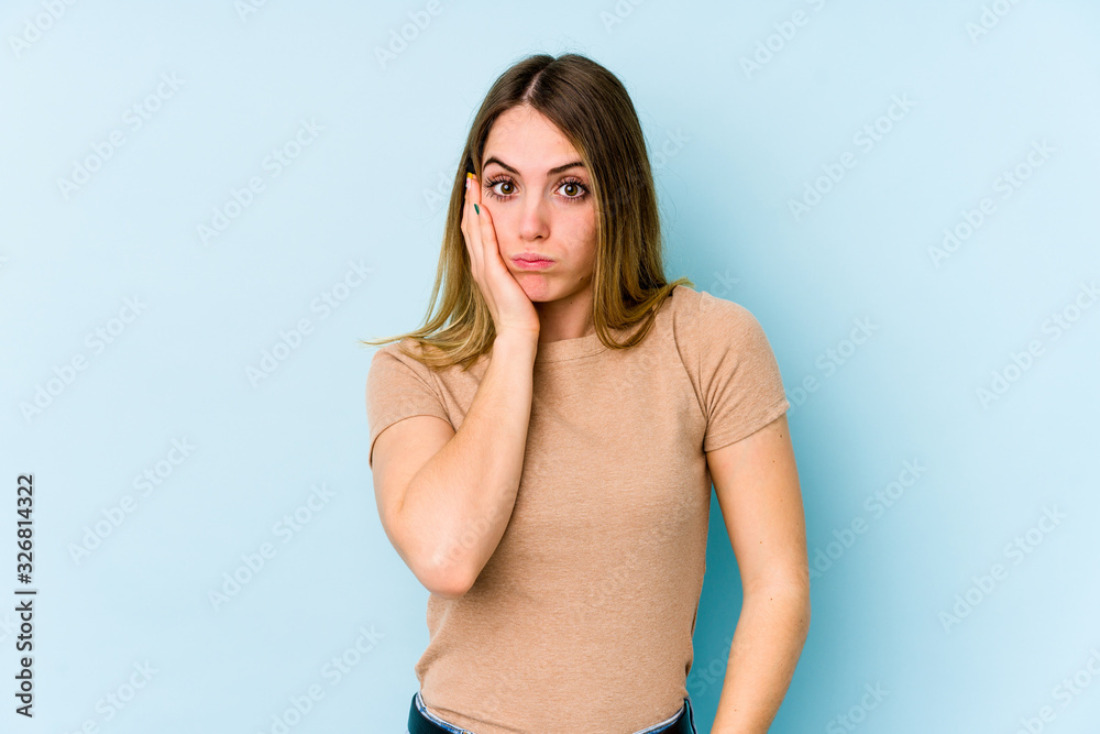 Young caucasian woman isolated on blue background blows cheeks, has tired expression. Facial expression concept. Young caucasian woman isolated on blue background blows cheeks, has tired expression. Facial expression concept.