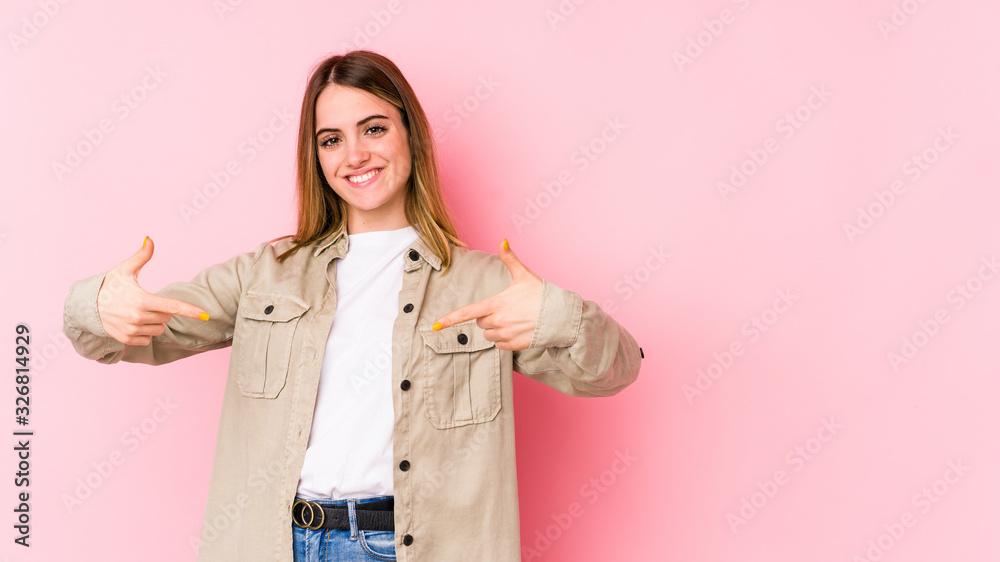 Young caucasian woman isolated on pink background points down with fingers, positive feeling. Young caucasian woman isolated on pink background points down with fingers, positive feeling.