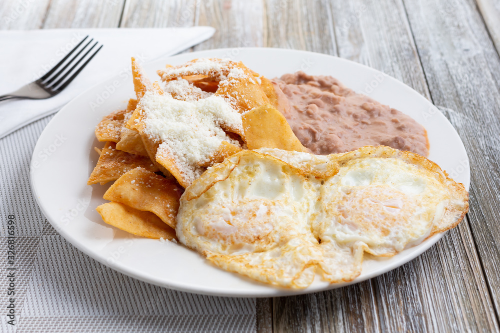 A view of a plate of huevos and chilaquiles, in a restaurant or kitchen setting.