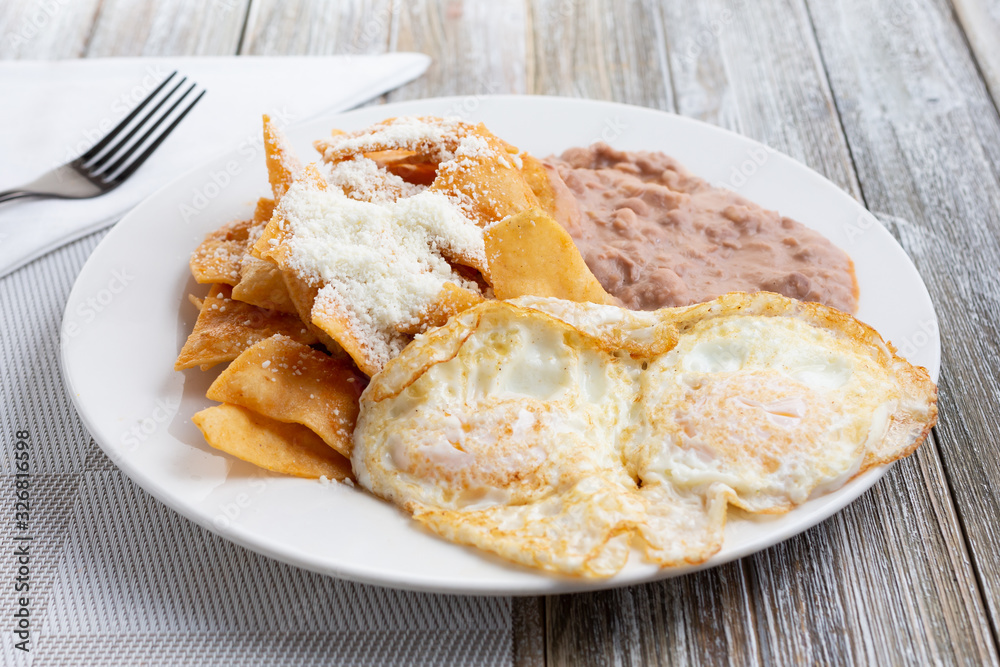 A view of a plate of huevos and chilaquiles, in a restaurant or kitchen setting. A view of a plate of huevos and chilaquiles, in a restaurant or kitchen setting.