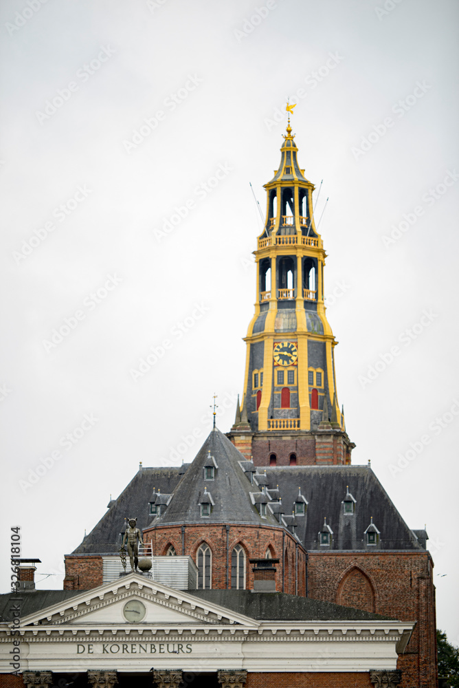 The tower of the Aa church in Groningen behind the former fish market and now supermarket in the Korenbeurs building with the statue of Hermes on top