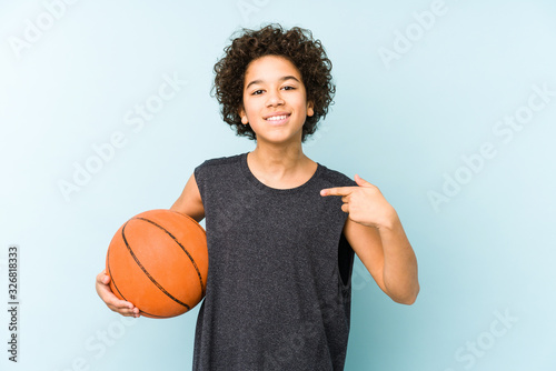 Obraz na płótnie Kid boy playing basketball isolated on blue background person pointing by hand t