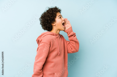 African american little boy isolated shouting and holding palm near opened mouth.
