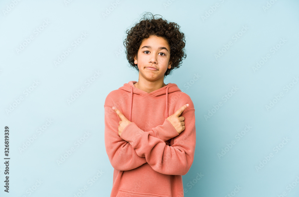 African american little boy isolated points sideways, is trying to choose between two options. African american little boy isolated points sideways, is trying to choose between two options.
