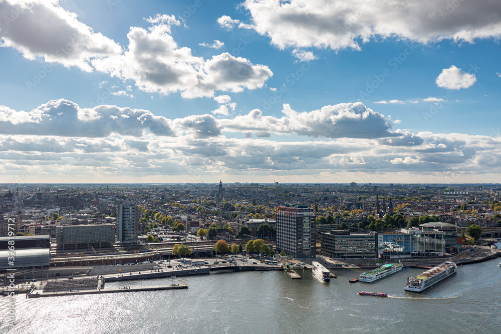 Port area in downtown Amsterdam, The Netherlands, seen from a high vantage point against a blue sky with clouds looking towards the historic city centre