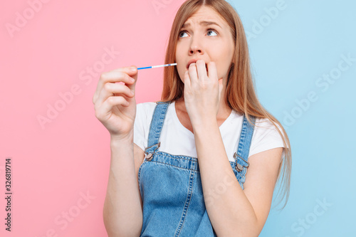 Shocked terrified young woman holds a pregnancy test