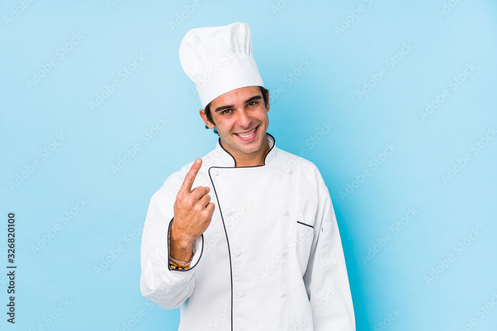 Young cook man isolated pointing with finger at you as if inviting come closer. Young cook man isolated pointing with finger at you as if inviting come closer.