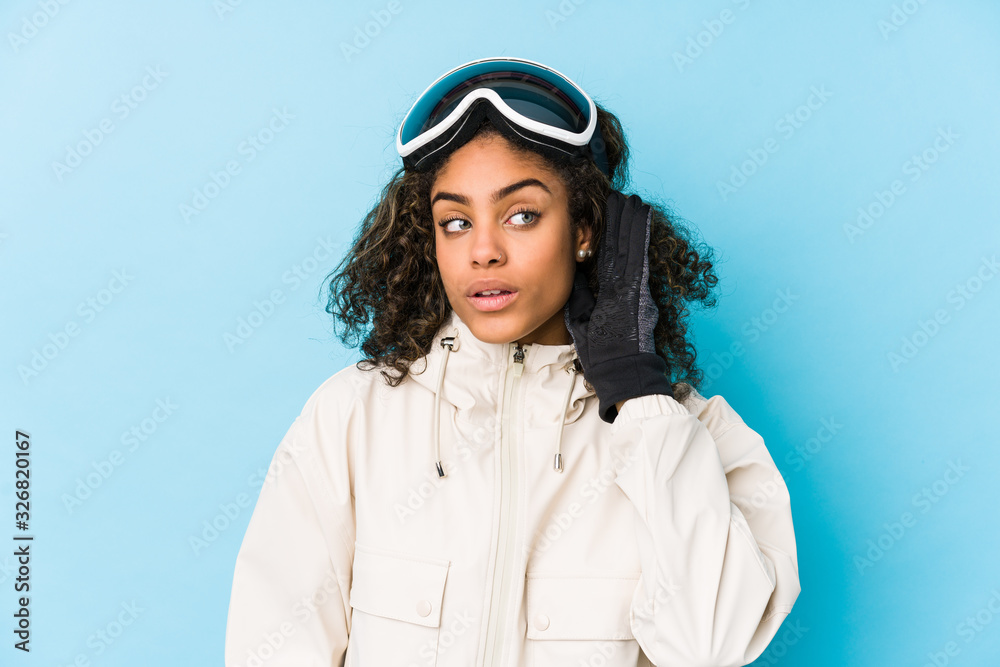 Young african american skier woman isolated trying to listening a gossip.