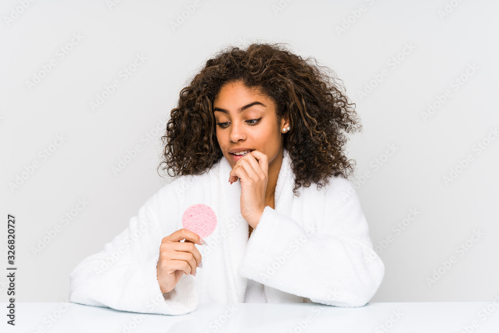 Young african american woman using a facial disk relaxed thinking about something looking at a copy space. Young african american woman using a facial disk relaxed thinking about something looking at a copy space.