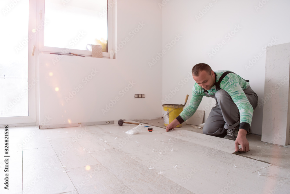 worker installing the ceramic wood effect tiles on the floor worker installing the ceramic wood effect tiles on the floor