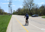 Man riding a bicycle in a bike lane in Morton Grove, Illinois as a car is turning  on to a street
