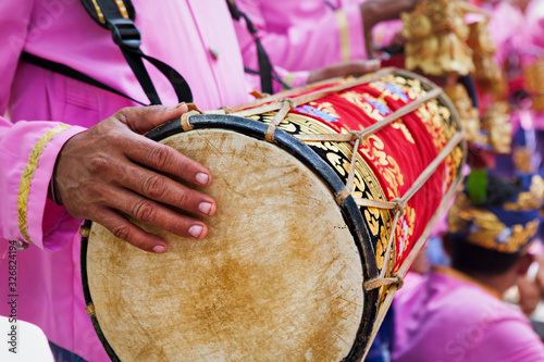 Balinese man play music on traditional drum Kendang -  musicians of Baleganjur (Gamelan) orchestra. Arts festivals in Indonesia, culture of Bali and Indonesian people. Asian travel background. photo