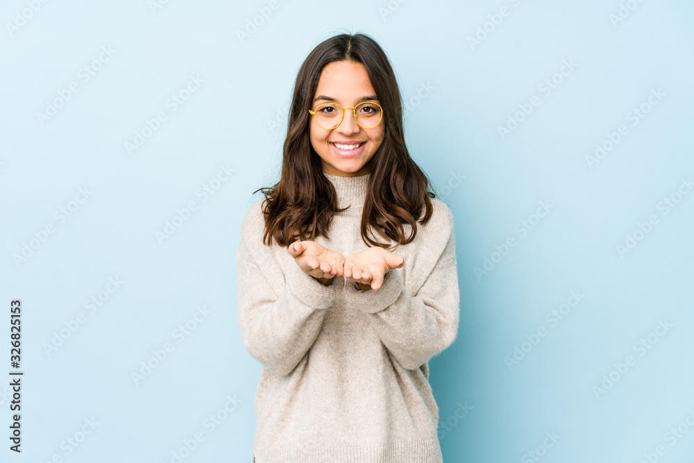 Young mixed race hispanic woman isolated holding something with palms, offering to camera. Young mixed race hispanic woman isolated holding something with palms, offering to camera.