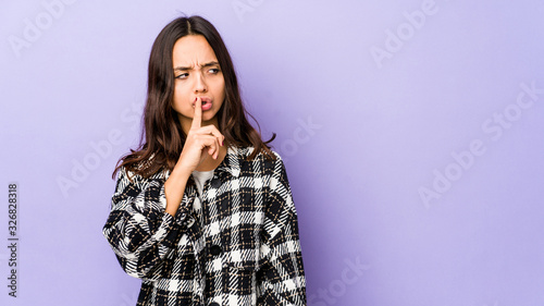 Young mixed race hispanic woman isolated keeping a secret or asking for silence. © Asier