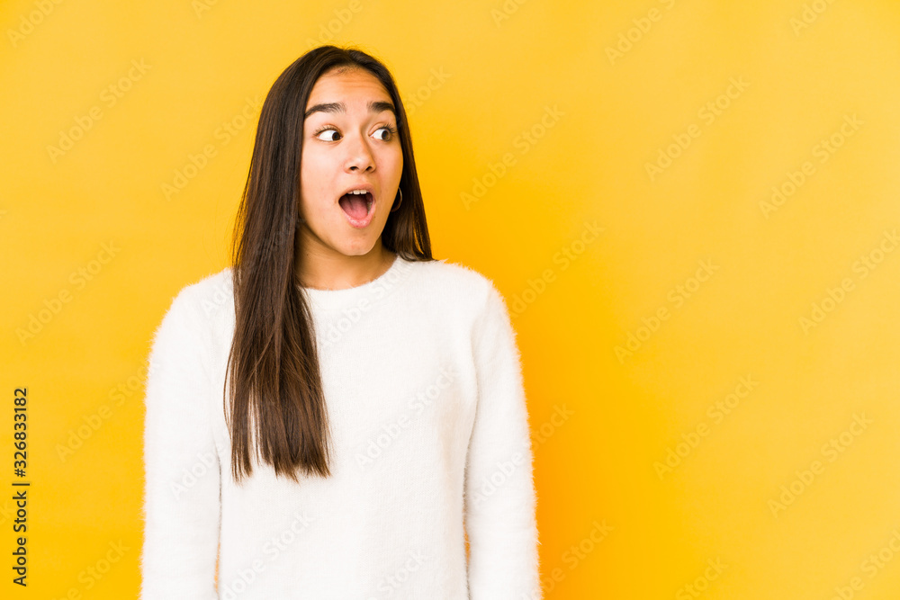 Young woman isolated on a yellow background being shocked because of something she has seen. Young woman isolated on a yellow background being shocked because of something she has seen.