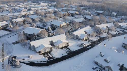 Aerial view of residential houses covered snow at winter season. Establishing shot of american neighborhood, suburb.  Real estate, drone shots, sunny morning, sunlight, from above. photo