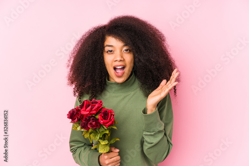 Young afro woman holding a roses isolated Young afro woman holding a rosessurprised and shocked.