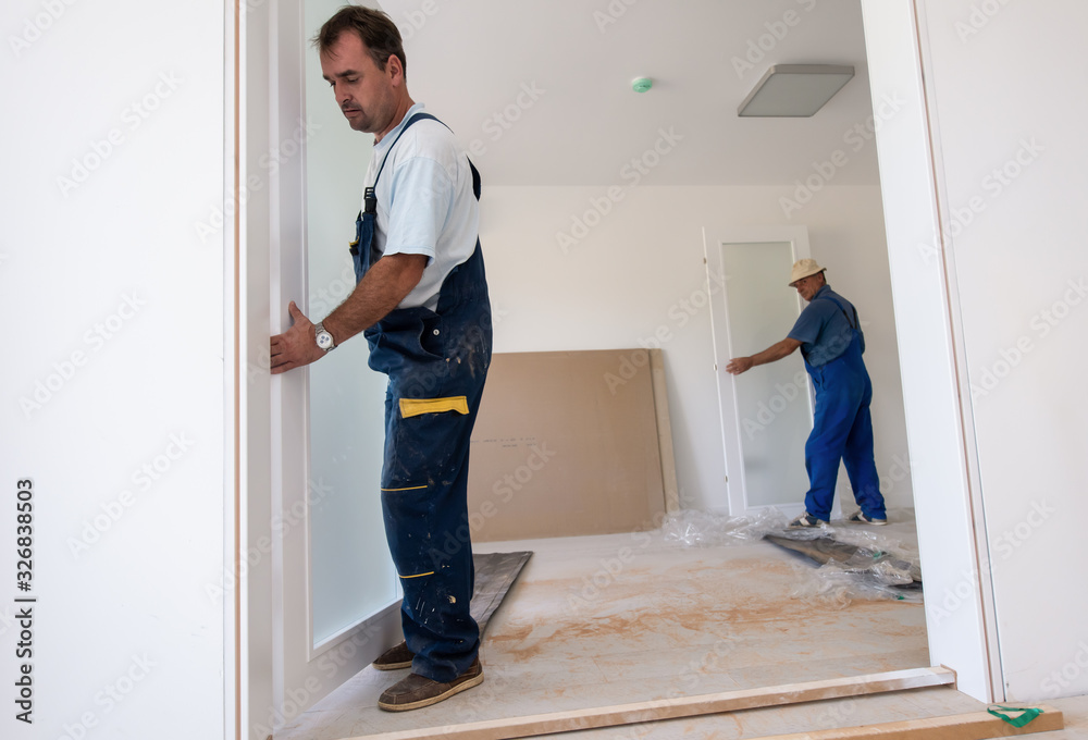 carpenters installing glass door with a wooden frame carpenters installing glass door with a wooden frame