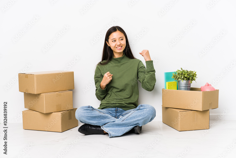 Young chinese woman moving to a new home raising fist after a victory, winner concept. Young chinese woman moving to a new home raising fist after a victory, winner concept.