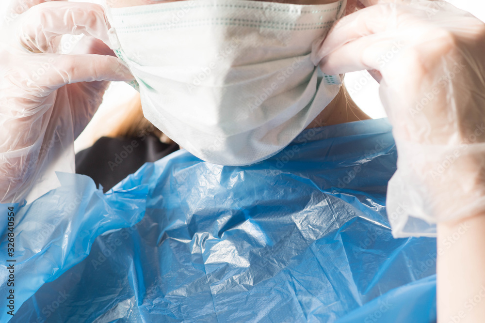 Woman, doctor, nurse putting on ffp2 surgical mask and gloves to protect herself from 2020-ncov Coronavirus in Tilburg, Netherlands