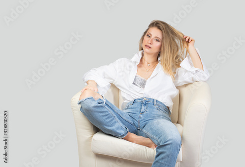 Beautiful woman in blue jeans and a white shirt in studio